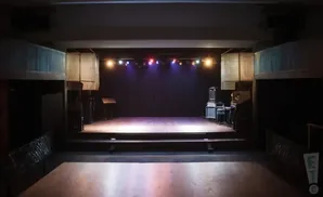 Empty stage with lighting rig, sound equipment, and audience seating area.