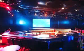 A futuristic TV studio with a large screen, lounge areas, and dramatic lighting.