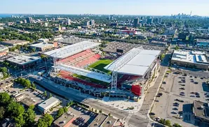 Aerial view of a soccer stadium surrounded by urban development under a clear blue sky.