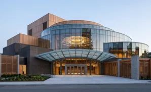 Modern building with curved glass facade, wood accents, and a slatted wooden screen.
