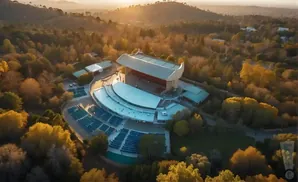 Aerial view of an outdoor amphitheater surrounded by trees with autumn foliage.