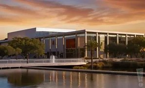 Modern building with glass facade at sunset, reflected in the water.