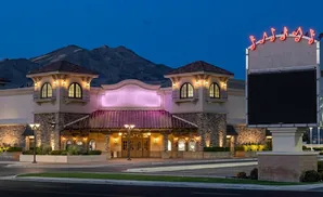A lit-up casino with musical notes on a sign, under a twilight sky with mountains in the background.