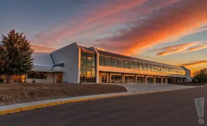 A modern building with a long glass-enclosed walkway during a vibrant sunset.