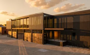 Modern building with glass facade and brick exterior at sunset.