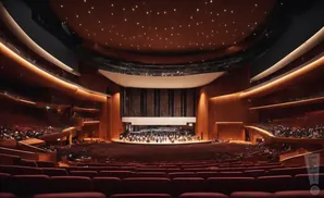 Interior view of a large, modern concert hall with tiered red seating and a warmly lit, star-ceiling.