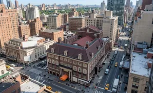 Aerial view of a bustling New York City street with tall buildings, traffic, and pedestrians.