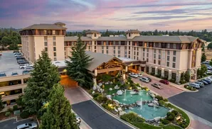 A large hotel with a rustic entrance, surrounded by trees and a pond.