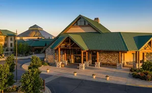 A lodge-style building with a green metal roof, stone accents, and large wooden columns at the entrance.