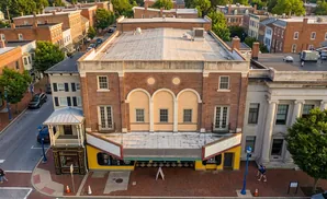 Aerial view of a brick building with arched windows and a marquee, surrounded by other historic buildings in a town.
