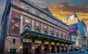 Town Hall theater in New York City with marquee lit up, at sunset.
