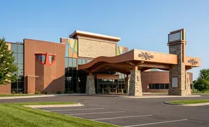 Modern brick building with a curved, copper-colored overhang and stone pillars.