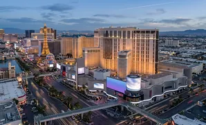 Las Vegas Strip at dusk, featuring the Eiffel Tower replica, hotels, casinos, and illuminated streets.