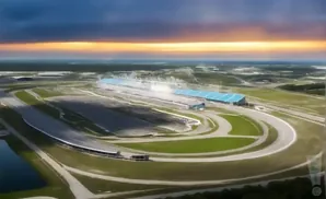 Aerial view of a race track with grandstands under a colorful sunset sky.