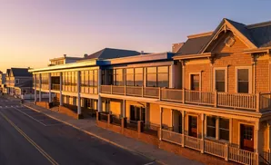 Sunset over buildings with balconies and a street in foreground.