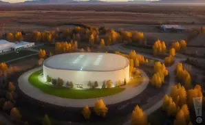 Aerial view of a large, round building surrounded by autumn trees at dusk.