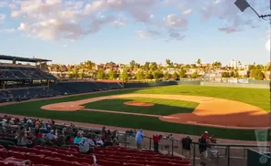 A baseball stadium during a game, with a baseball field and spectators in the stands.