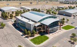 Aerial view of Tingley Coliseum, a large domed building with a curved facade, surrounded by parking lots and some greenery.