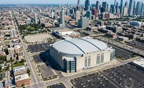Aerial view of a large, domed stadium surrounded by parking lots and city buildings.