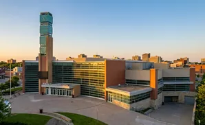 Tribute Communities Centre in Canada, featuring a tall clock tower and modern architecture, during a sunset.