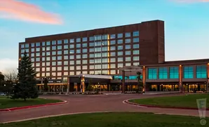 A large brick hotel with a modern glass-fronted wing is lit up at dusk.