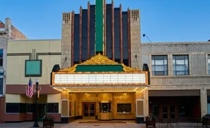 An old-fashioned theater marquee with lights and a blank sign, an American flag and a lamppost in front.