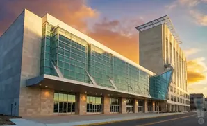 Modern conference center with glass facade and stone accents at sunset.