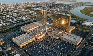 Aerial view of a resort complex with two golden skyscrapers, surrounding buildings, and extensive parking lots.