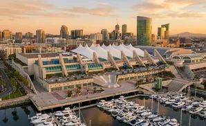 San Diego Convention Center with boats docked in the harbor and a city skyline at sunset.