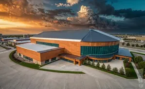 Modern building with wood accents and a large glass facade under a dramatic, cloudy sky.