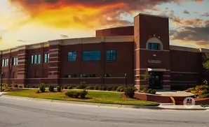 Brick building with arched windows under a dramatic sunset sky.