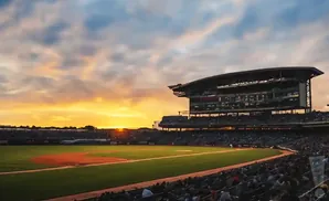 Sunset over a baseball stadium with the field and stands visible.