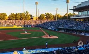 A baseball pitcher throws a ball to a batter during a game at a stadium filled with spectators.