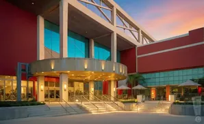 Modern building entrance with large windows, red exterior, and grand staircase.