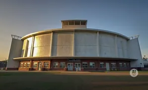 A circular building with a domed roof and a clock tower on top, bathed in golden sunset light.