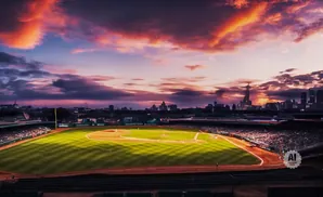 Baseball stadium at sunset with a city skyline and dramatic clouds.