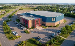 Aerial view of a large blue and brick building with a parking lot.