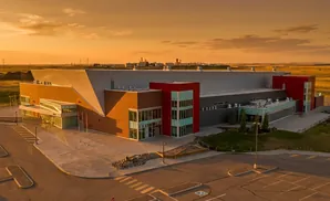 Exterior aerial view of a modern industrial building with brick and red accents at sunset.