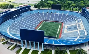 Aerial view of a large, mostly empty football stadium with blue seats and a green field.