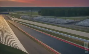 Aerial view of a racetrack at sunset, with the sky painted in shades of orange and pink.