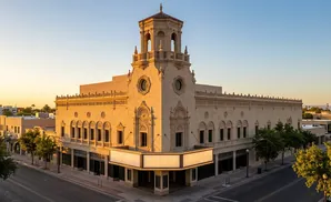 Exterior view of a historic theater building with a tower at sunset.