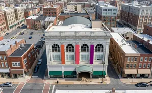 Aerial view of a city street with brick buildings and an ornate white building with colorful banners.