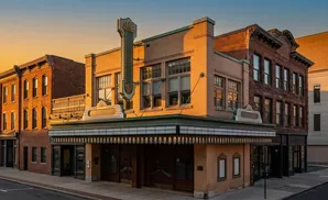 Art deco theater with marquee and vintage signage on a street at sunset.