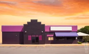A purple and dark brown commercial building with a bright orange sky overhead.