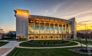 Modern building with a large glass facade and concrete accents at sunset.