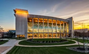 Modern building with a glass facade and concrete accents at sunset.