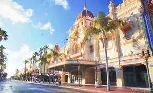 Ornate vintage theater with palm trees on a sunny day.