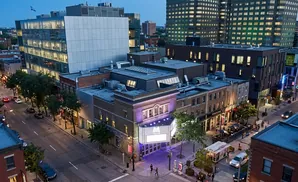 Aerial view of a street with buildings, cars, and people at dusk.