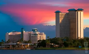 A hotel complex by the water at sunset, with vibrant pink and blue clouds.