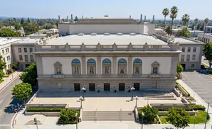 Grand building with columns, arched windows, and a balustrade, set against a clear blue sky.